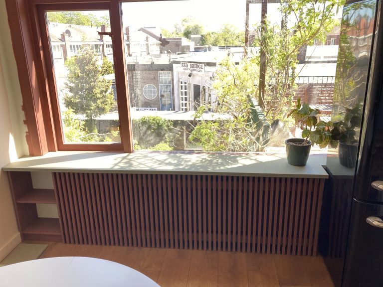 Raambank met maatwerk radiatorombouw in verticale houten latten — Senders Meubelmakerij